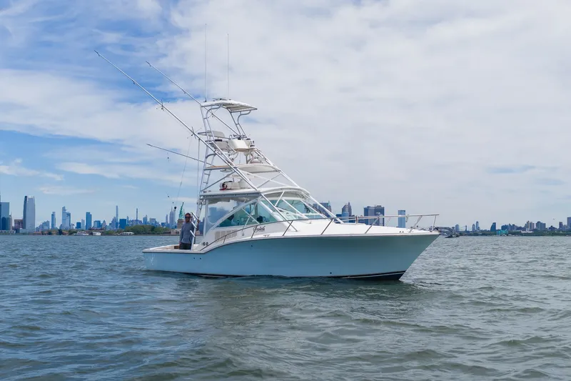Slide: The Image of A white boat with a tall helm station cruises on calm water against a city skyline. - 1
