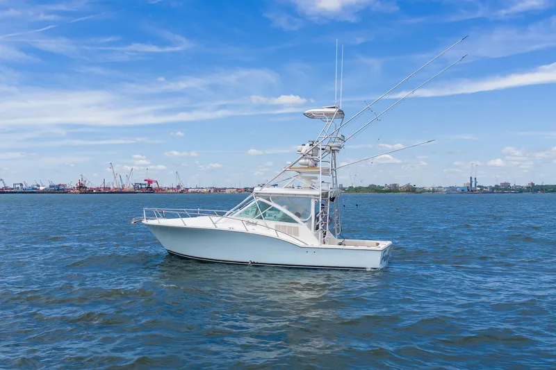 Slide: The Image of A white boat on the water with a clear blue sky and a city in the background. - 2