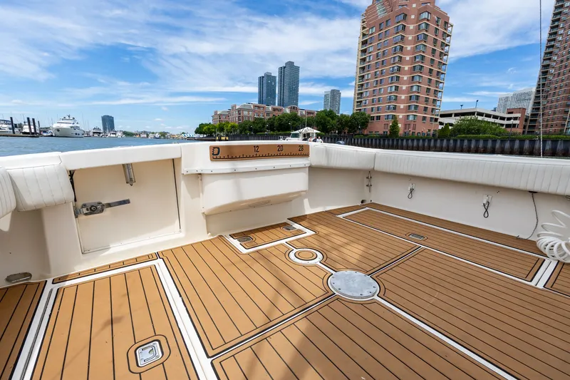 Slide: The Image of The image shows a spacious boat deck with wooden flooring and an urban skyline in the background. - 23
