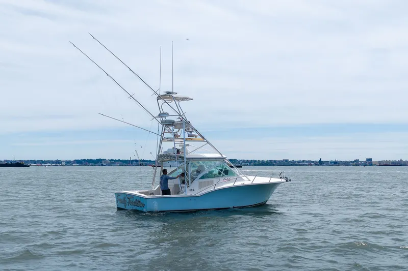 Slide: The Image of A 2011 Carolina Classic 32 boat on calm water, equipped with fishing rods. - 3