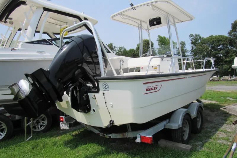 The Image of 2013 Boston Whaler 190 Montauk boat on trailer, featuring outboard motor and T-top. - 0