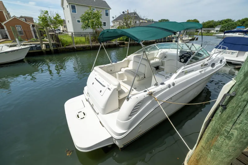 Slide: The Image of 2002 Searay 260 Sundancer boat docked in a serene marina setting. - 2