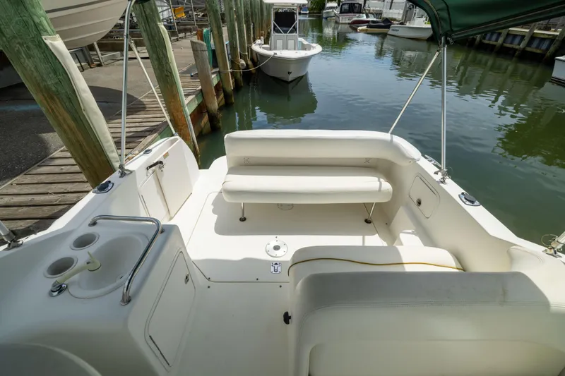 Slide: The Image of 2002 Searay 260 Sundancer boat interior with seating and cup holders at a marina. - 21