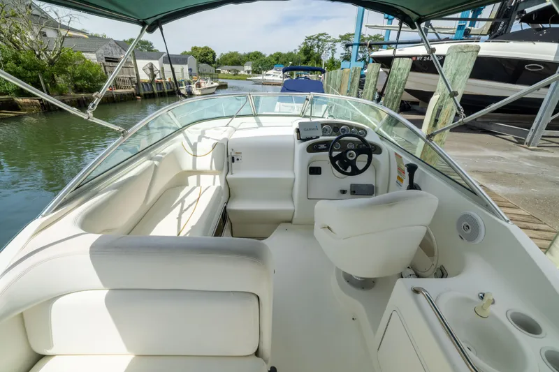 Slide: The Image of 2002 Searay 260 Sundancer boat interior with helm, seating, and canopy in a marina setting. - 22
