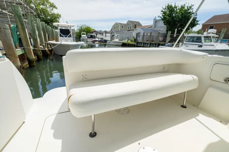 Slide: The Image of 2002 Searay 260 Sundancer boat interior with white seating in a marina setting. - 26