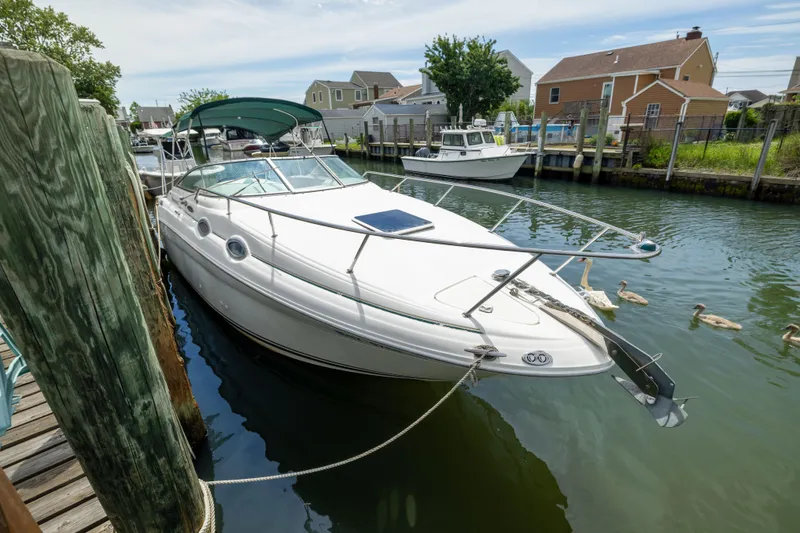 Slide: The Image of 2002 Searay 260 Sundancer docked in a serene canal with nearby houses. - 4