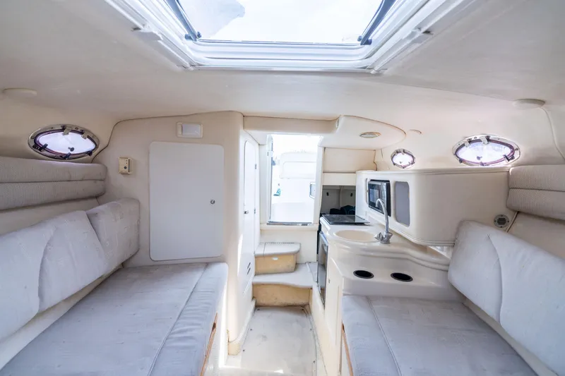 Slide: The Image of Interior of 2002 Searay 260 Sundancer boat, featuring cozy seating and compact kitchenette. - 5