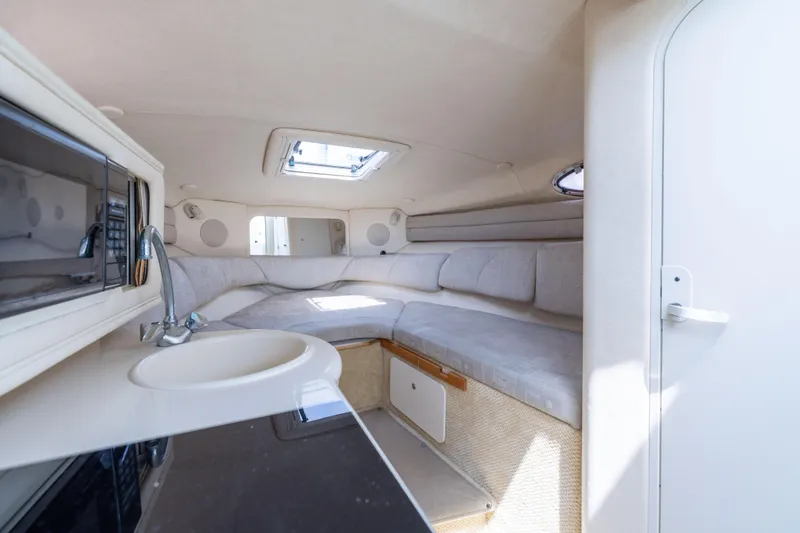 Slide: The Image of Interior of 2002 Searay 260 Sundancer boat, featuring cozy seating and compact kitchenette. - 6