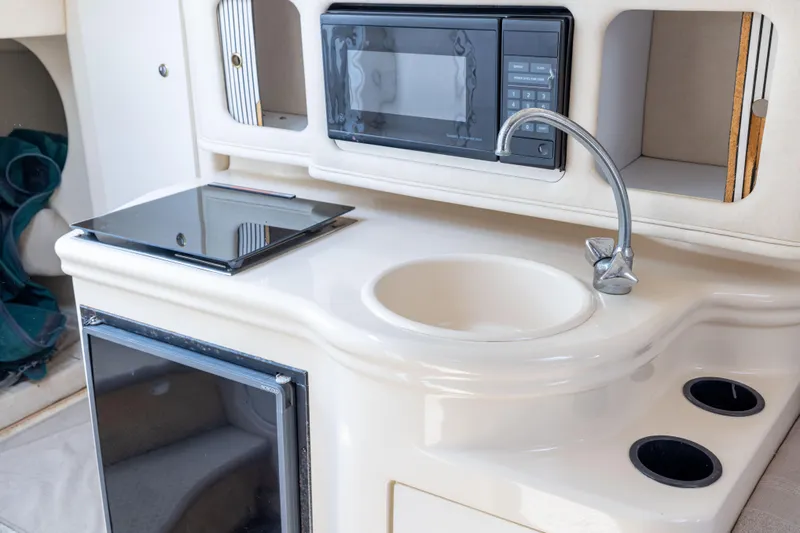 Slide: The Image of 2002 Searay 260 Sundancer kitchenette with sink, microwave, and stove. - 8