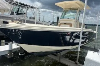 Slide: The Image of 2014 Scout 240 Bay Scout boat docked on lift under cloudy sky. - 4