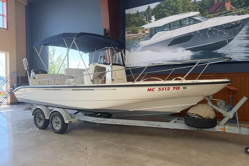 The Image of 2004 Boston Whaler 220 Dauntless boat on trailer in showroom with canopy. - 1