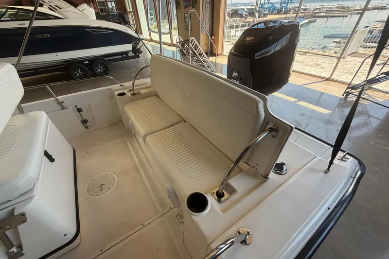 Slide: The Image of 2004 Boston Whaler 220 Dauntless interior with seating and outboard motor, dockside view. - 4