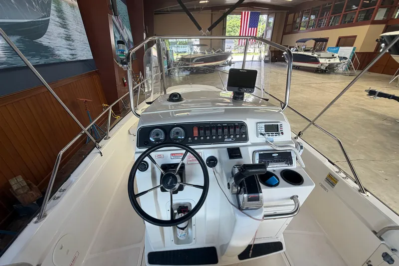 Slide: The Image of 2004 Boston Whaler 220 Dauntless boat cockpit with steering wheel and control panel in showroom. - 5