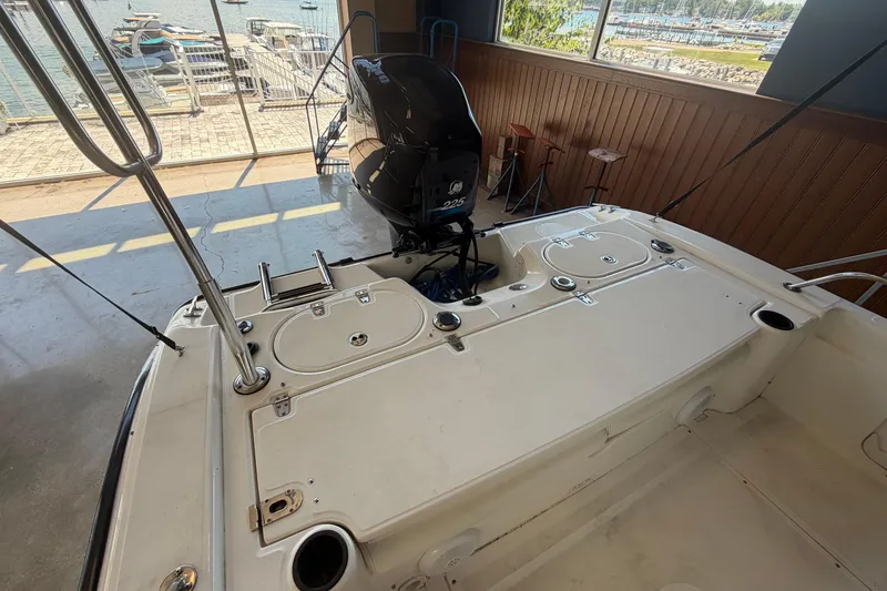 Slide: The Image of 2004 Boston Whaler 220 Dauntless boat interior with motor, docked in a marina. - 8