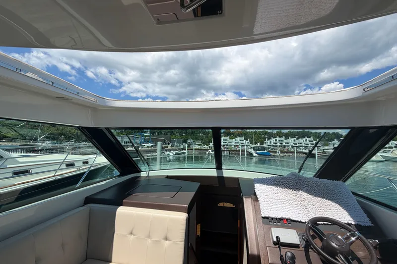 Slide: The Image of Interior view of 2016 Tiara Yachts C39 Coupe, showcasing helm and marina backdrop. - 21