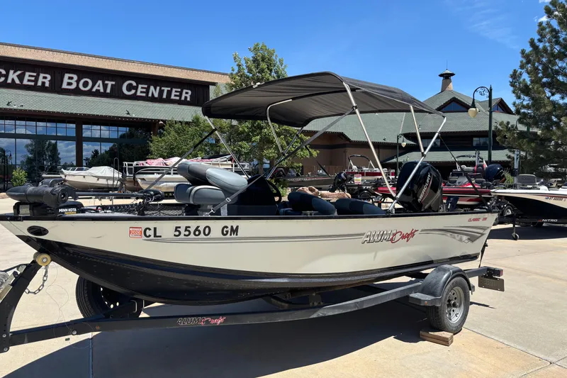 Slide: The Image of 2021 Alumacraft Classic 165 boat with canopy at a boat center, parked on a trailer. - 1