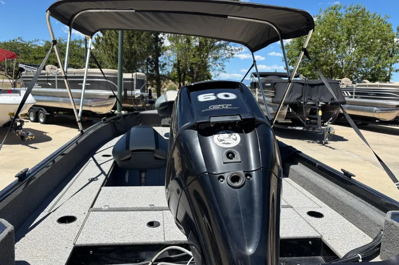 Slide: The Image of 2021 Alumacraft Classic 165 boat with 60 HP engine, parked outdoors under a canopy. - 10