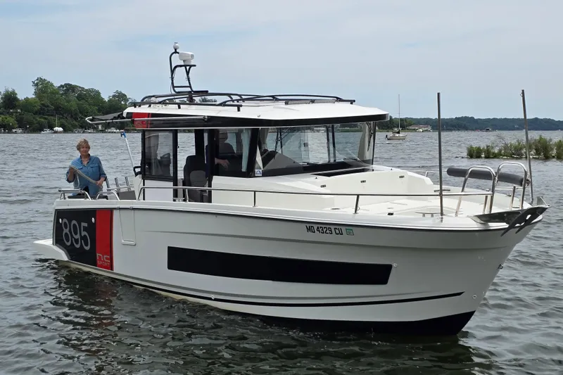 The Image of 2023 Jeanneau NC Sport 895 boat cruising on a lake with a person onboard. - 3