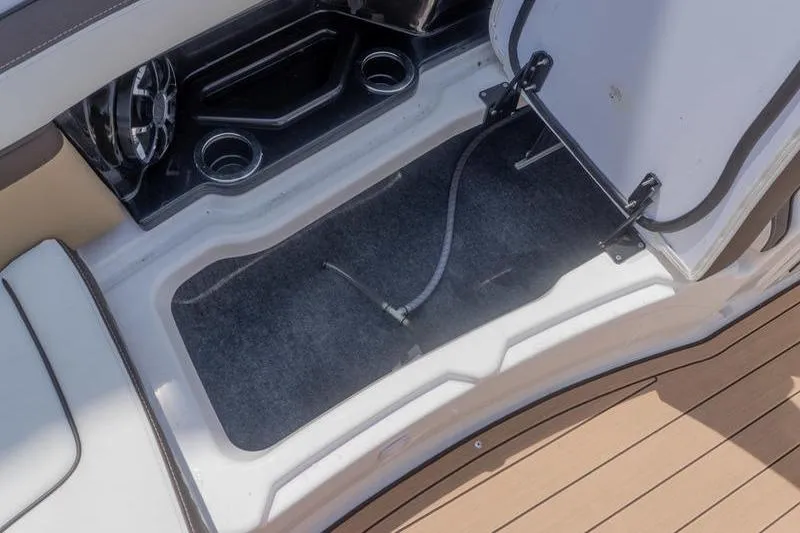 Slide: The Image of Open storage compartment on 2023 Yamaha Boats 275SDX, featuring cup holders and speaker. - 18
