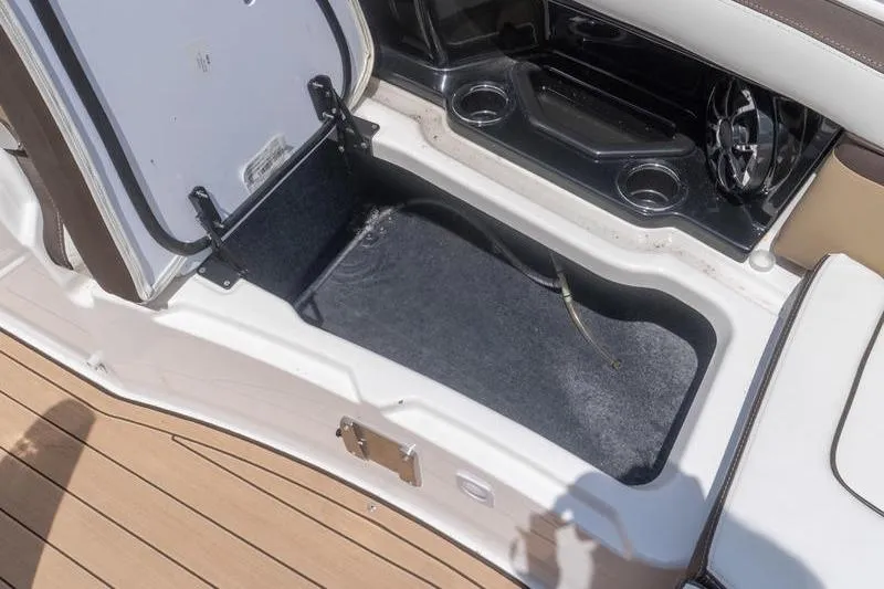 Slide: The Image of Open storage compartment on 2023 Yamaha Boats 275SDX, featuring cup holders and sleek design. - 19