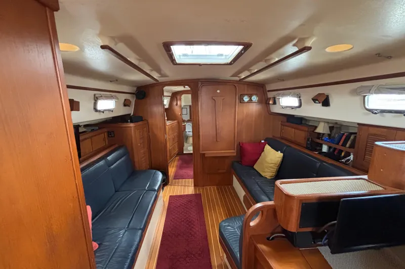 Slide: The Image of Interior of 1999 Island Packet 45 sailboat with wood finish and blue seating. - 10