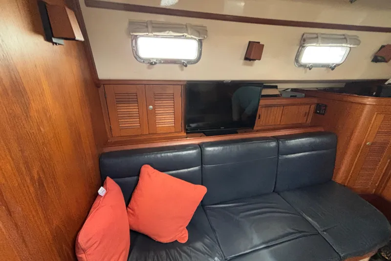 Slide: The Image of Interior of 1999 Island Packet 45 yacht with leather sofa, orange cushions, and wooden cabinetry. - 17