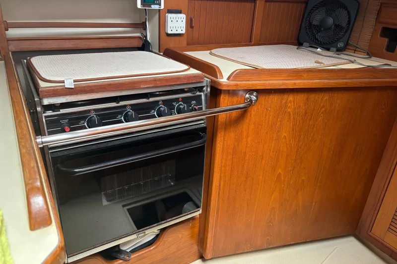 Slide: The Image of Interior of a 1999 Island Packet 45 yacht featuring a wooden kitchen with an oven. - 7