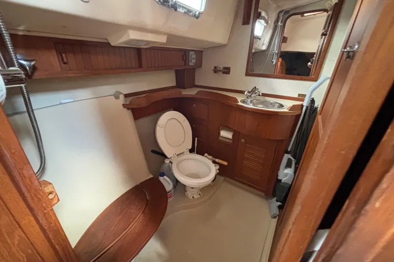 Slide: The Image of Bathroom interior of a 1999 Island Packet 45 yacht, featuring wooden cabinetry and compact design. - 9