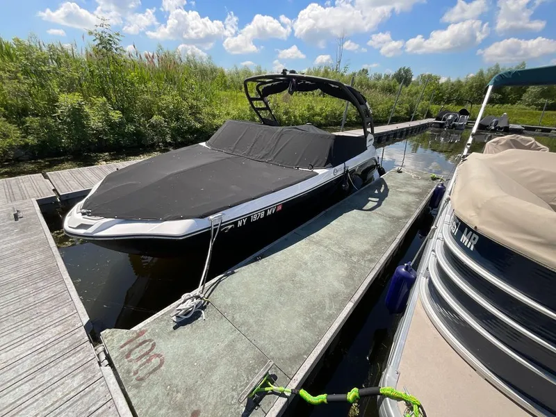 The Image of A 2025 Yamaha 222SD boat docked, covered with a black tarp, surrounded by greenery. - 0