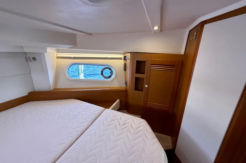 Slide: The Image of 2025 Beneteau Swift Trawler 41 Fly cabin interior with bed and porthole view. - 27