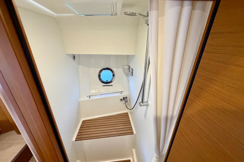 Slide: The Image of Shower area in 2025 Beneteau Swift Trawler 41 Fly, featuring wooden slats and porthole window. - 29