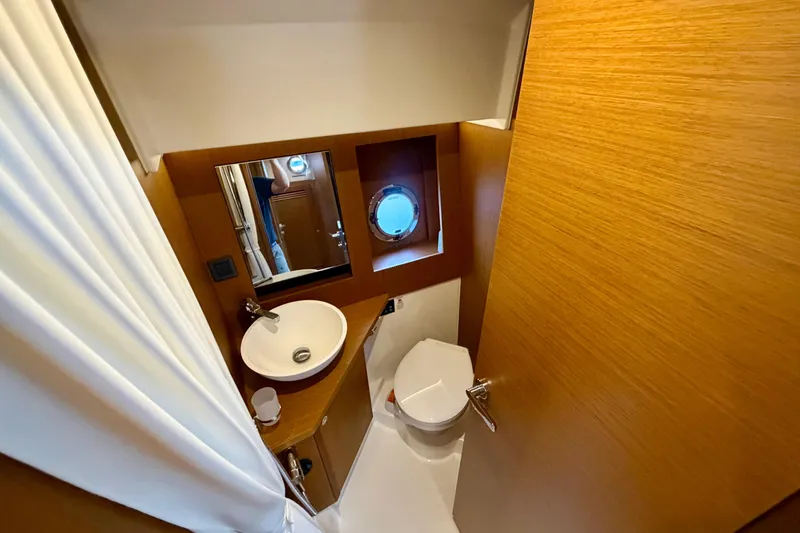 Slide: The Image of Bathroom interior of 2025 Beneteau Swift Trawler 41 Fly, featuring modern fixtures and porthole window. - 33