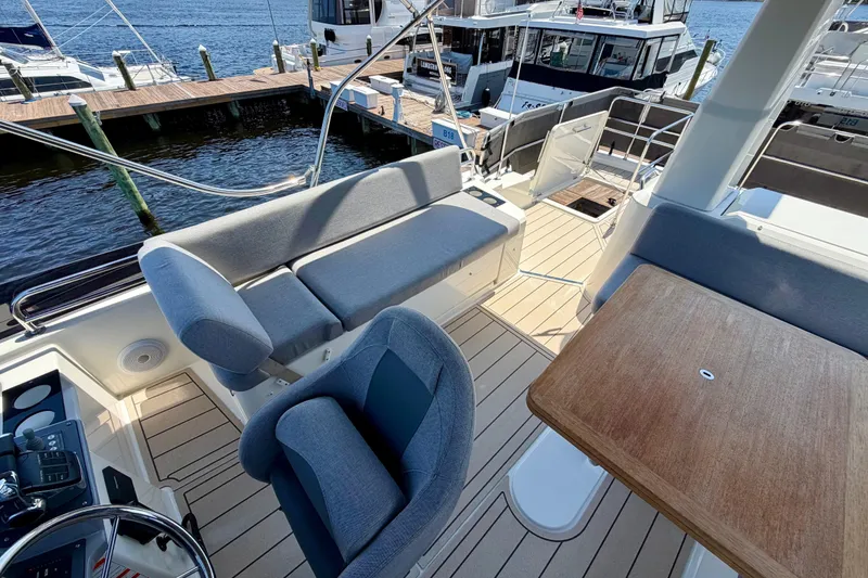 Slide: The Image of Flybridge of 2025 Beneteau Swift Trawler 41 Fly with seating and table, docked at marina. - 8