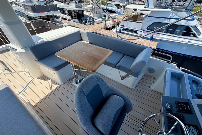 Slide: The Image of Flybridge of 2025 Beneteau Swift Trawler 41 Fly with seating and table, docked at marina. - 9