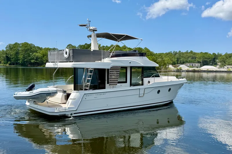Slide: The Image of 2025 Beneteau Swift Trawler 41 Fly cruising on a serene lake under a clear blue sky. - 6