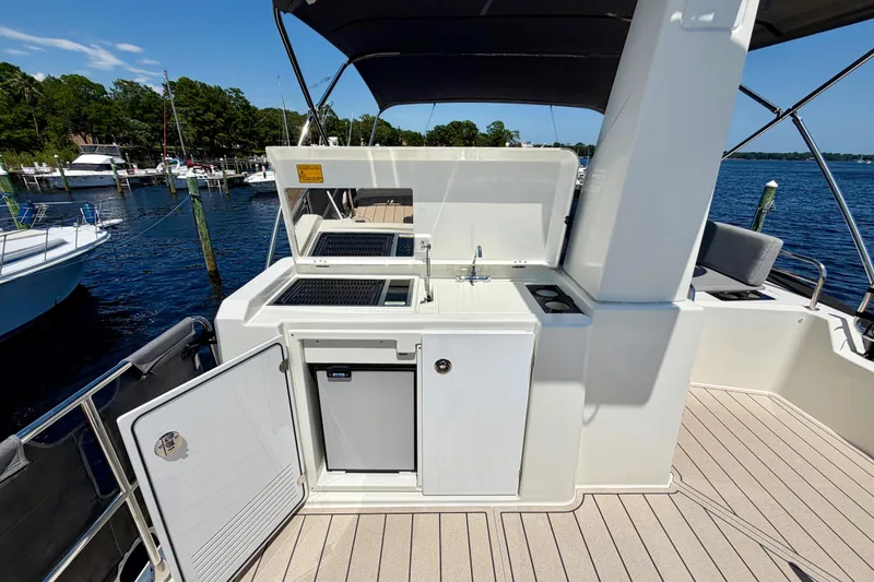 Slide: The Image of 2025 Beneteau Swift Trawler 41 Fly deck with outdoor kitchenette and scenic marina view. - 11