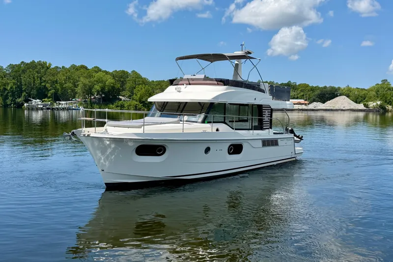 Slide: The Image of 2025 Beneteau Swift Trawler 41 Fly cruising on a serene lake under a clear sky. - 1