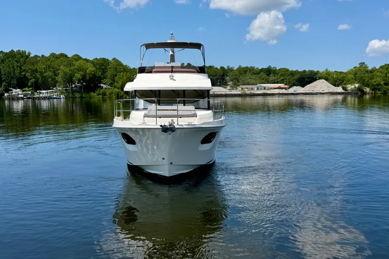 Slide: The Image of 2025 Beneteau Swift Trawler 41 Fly on serene water, surrounded by lush greenery. - 2