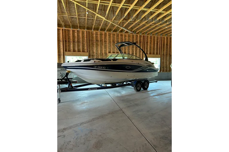 The Image of 2015 Hurricane SunDeck 2400 IO boat on trailer in a wooden garage. - 0