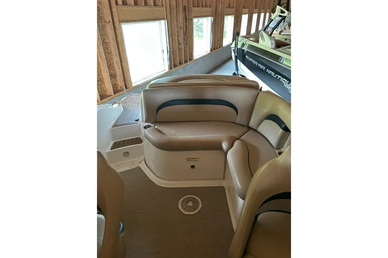 Slide: The Image of 2015 Hurricane SunDeck 2400 IO boat interior with beige seating in a wooden boathouse. - 3