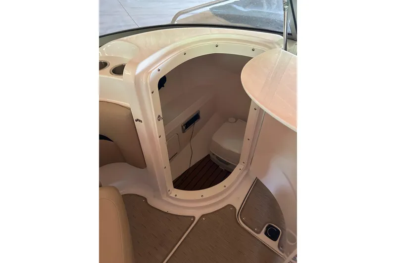 Slide: The Image of Interior view of 2015 Hurricane SunDeck 2400 IO boat, featuring a compact restroom area. - 4