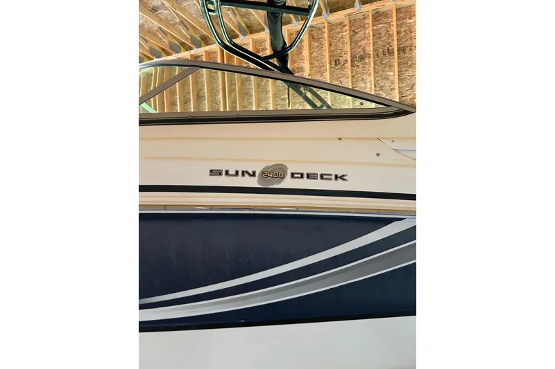 Slide: The Image of 2015 Hurricane SunDeck 2400 IO boat side view in storage, showcasing sleek design. - 6