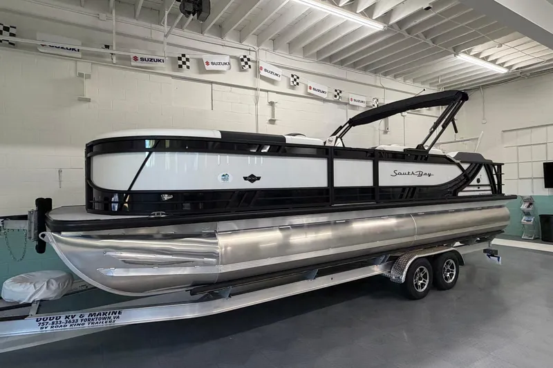 The Image of 2026 South Bay 525SB2 pontoon boat on trailer in showroom. - 0