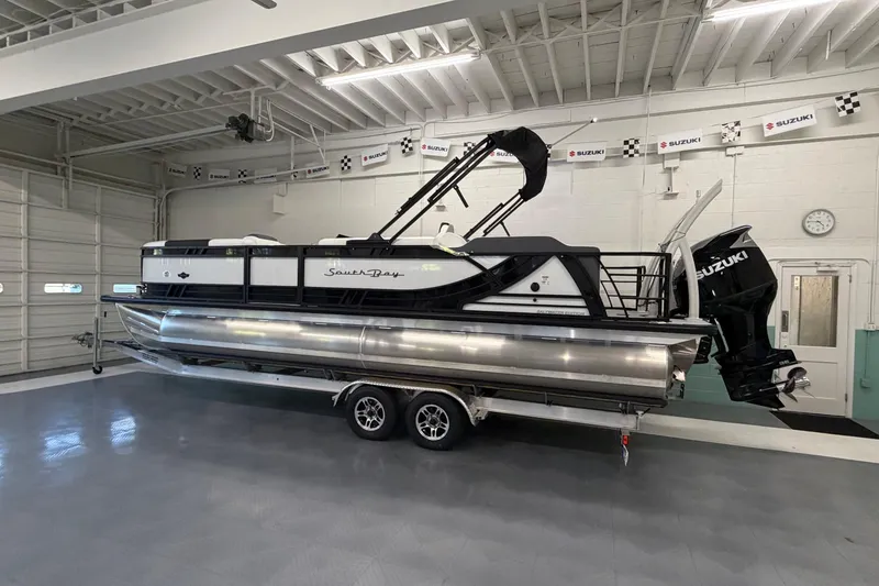 Slide: The Image of 2026 South Bay 525SB2 pontoon boat with Suzuki engine in a showroom. - 2