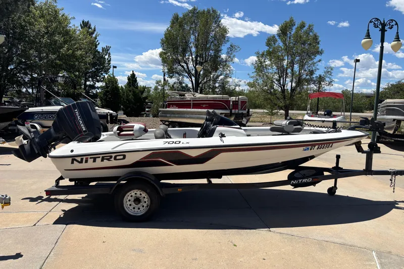 The Image of 1998 Nitro 700 LX DC boat on trailer, parked outdoors under a clear blue sky. - 0