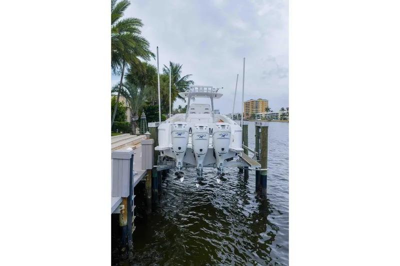 Slide: The Image of 2019 Intrepid 400 Center Console boat docked by palm trees and waterfront buildings. - 10