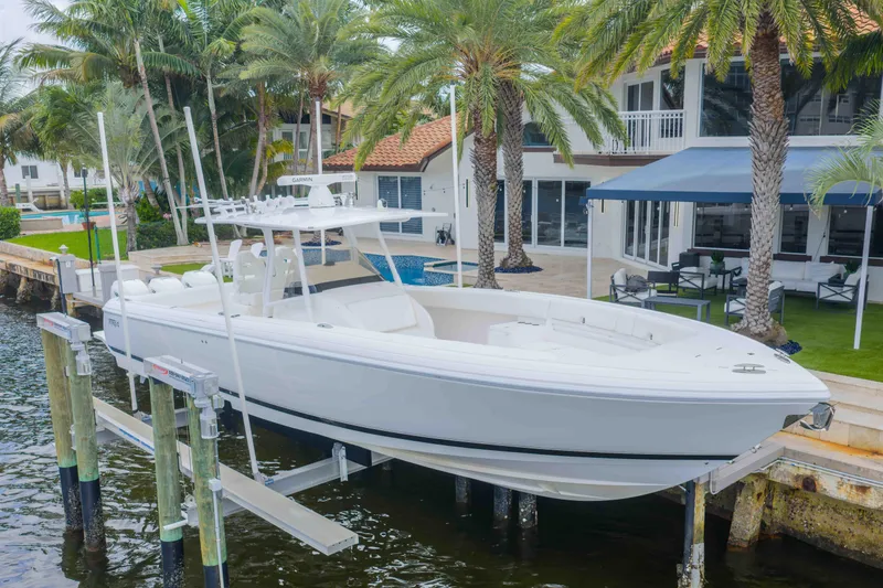 Slide: The Image of 2019 Intrepid 400 Center Console boat docked near waterfront home with palm trees. - 0