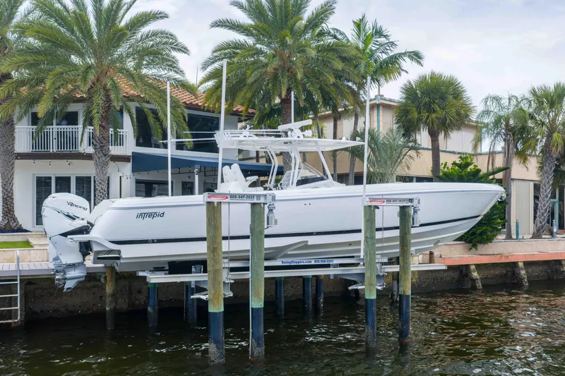 The Image of 2019 Intrepid 400 Center Console boat docked near waterfront home with palm trees. - 1