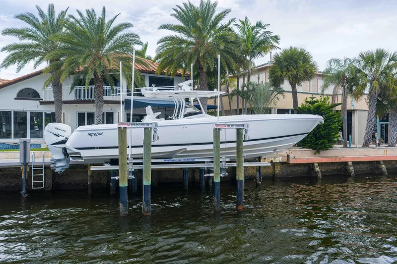 Slide: The Image of 2019 Intrepid 400 Center Console boat docked near waterfront home with palm trees. - 2