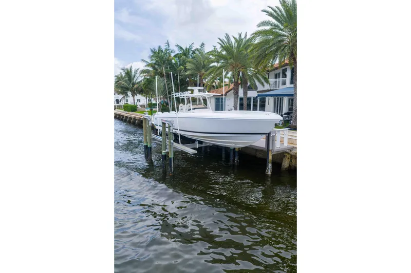 Slide: The Image of 2019 Intrepid 400 Center Console boat docked near palm trees and waterfront homes. - 9